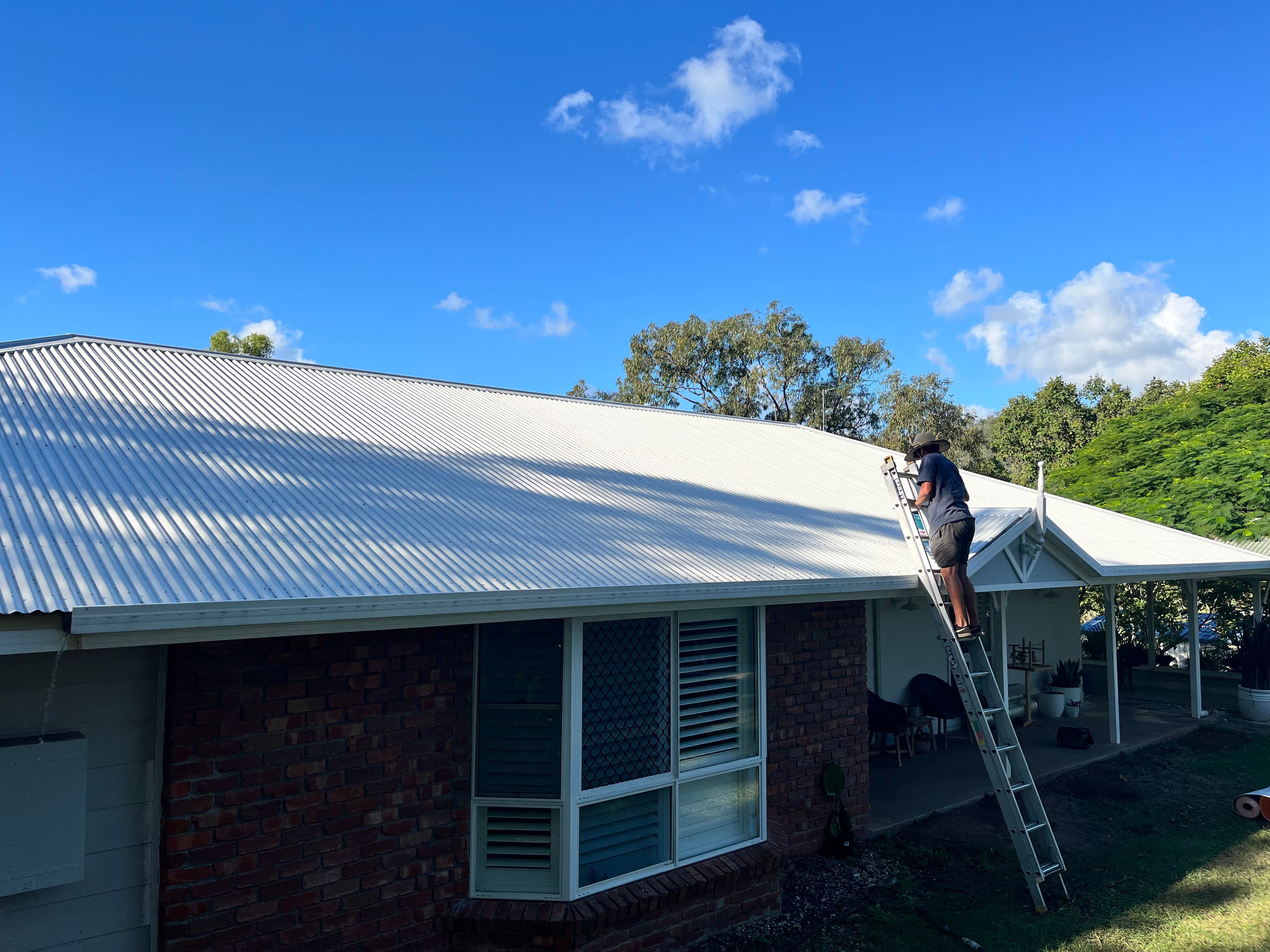 Re-roof on brick home with worker on ladder