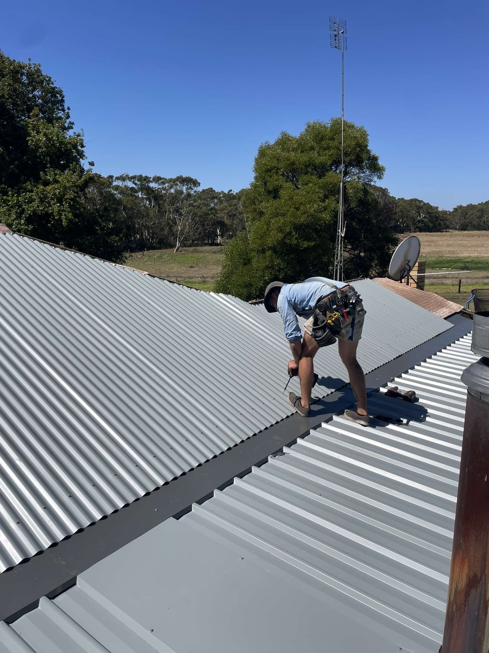 Roofer screwing down corrugated iron